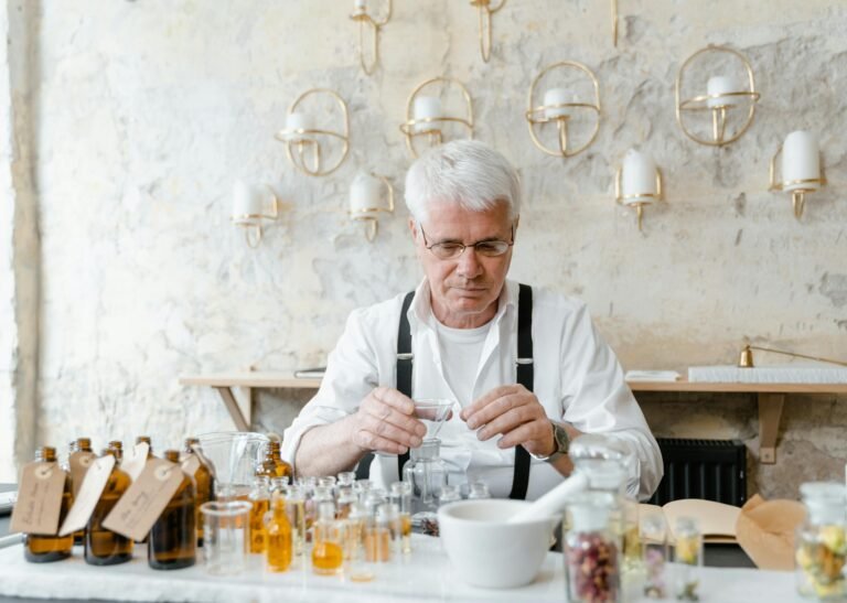 Senior man with glasses inspecting bottles of perfumes at home.